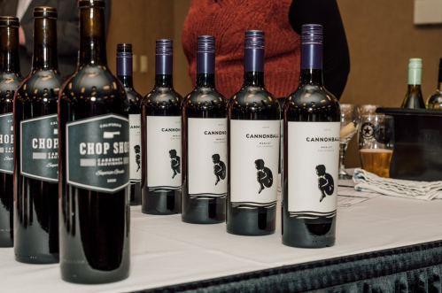 A table displaying several bottles of wine, including "Chop Shop" and "Cannonball," at a tasting event.