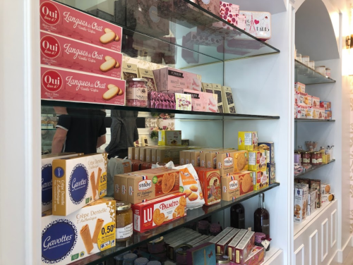 Shelves filled with various packaged snacks and sweets, including cookies and candies, in a bright store setting.