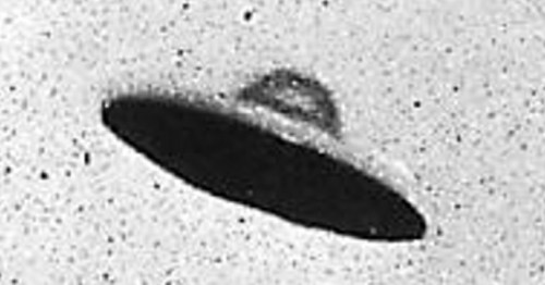 A black and white image of a flying saucer-shaped object against a speckled background.