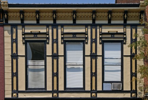 Facade of a building featuring three windows with decorative trim and contrasting colors.