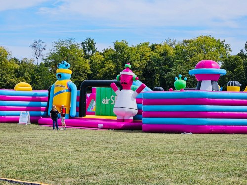 Colorful inflatable structures in a grassy field, featuring playful designs and a clear blue sky above.