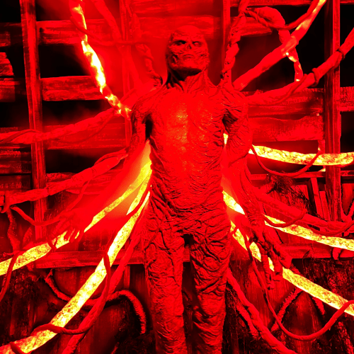 A humanoid figure with multiple glowing red tendrils, set against a dark background with an eerie, ominous atmosphere.