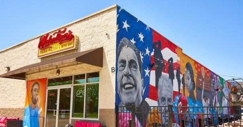 Colorful mural on a building featuring various portraits and an American flag, with a sign for a restaurant and bar.