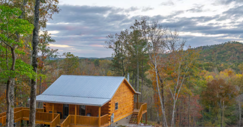 A log cabin sits on a bluff overlooking Alabama's mountains in the fall.