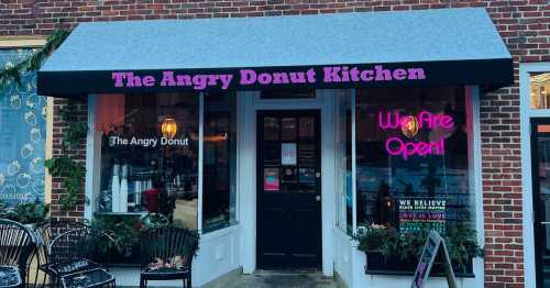 Exterior of The Angry Donut Kitchen, featuring a sign that says "We Are Open!" and outdoor seating.