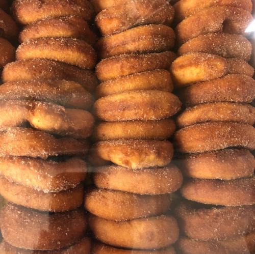 A close-up of stacked, golden-brown donuts coated in cinnamon sugar.
