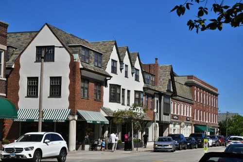 Charming street view of historic buildings with shops, cars parked, and clear blue sky above.