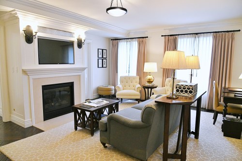 Cozy living room with a fireplace, comfortable seating, and large windows, featuring elegant decor and warm lighting.