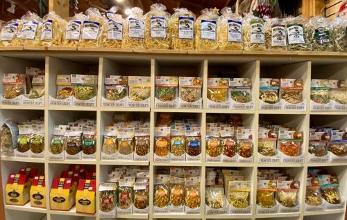A neatly organized display of various pasta and dried goods in clear bags on shelves.
