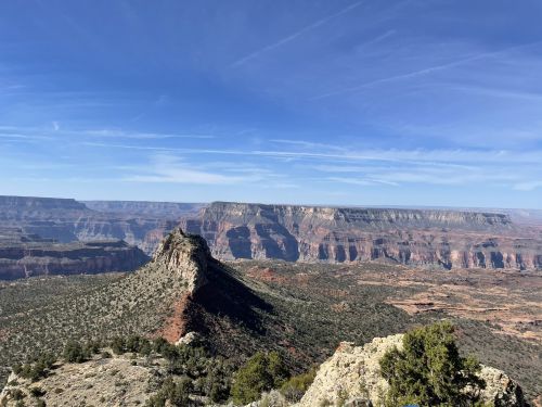 A panoramic view of rugged cliffs and a prominent rock formation under a clear blue sky.