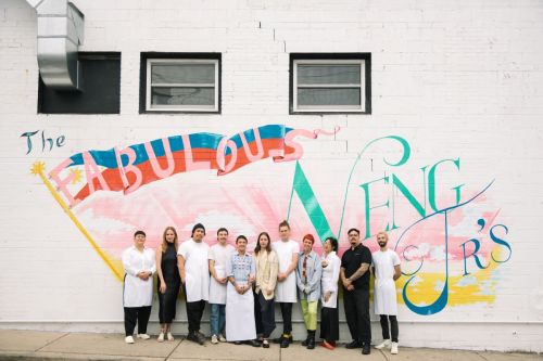 A group of people in white aprons stands in front of a colorful mural that reads "The Fabulous Weng's."