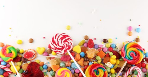 An assortment of candy, gumdrops, and lollipops against a white backdrop.