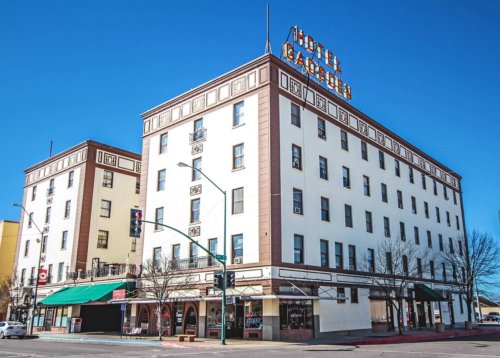 Historic Hotel Garden building with a prominent sign, featuring a three-story facade and clear blue sky.