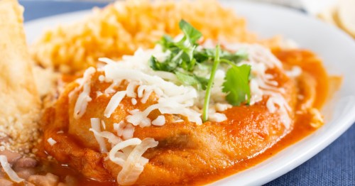 A view of a plate of chile relleno, fried pepper, with rice and garnish on top
