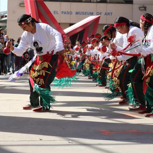 A group of dancers in traditional attire perform with instruments at the El Paso Museum of Art.