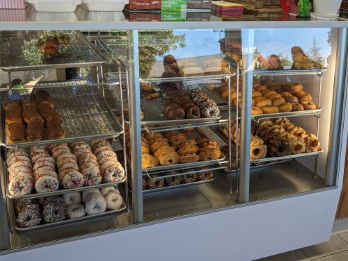 A display case filled with various donuts, including glazed, chocolate, and sprinkled varieties.