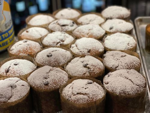 A close-up of freshly baked muffins dusted with powdered sugar, arranged in a tray.