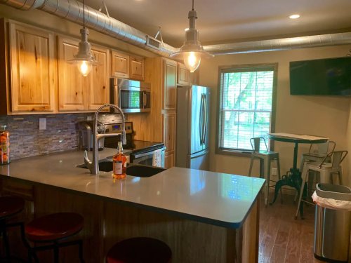 Modern kitchen with wooden cabinets, stainless steel appliances, a large island, and a dining table by the window.