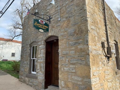 Stone building exterior with a sign reading "Buffalo Springs Distilling Co." and a wooden door.