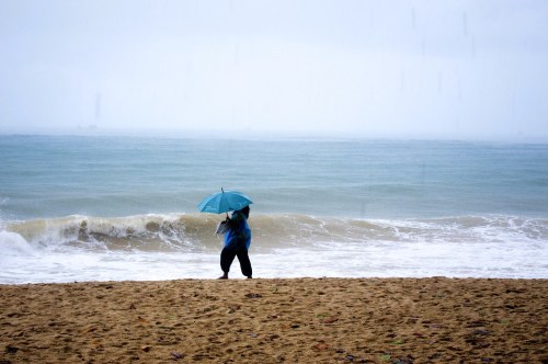Woman walking with an umbrella on a scenic beach in winter