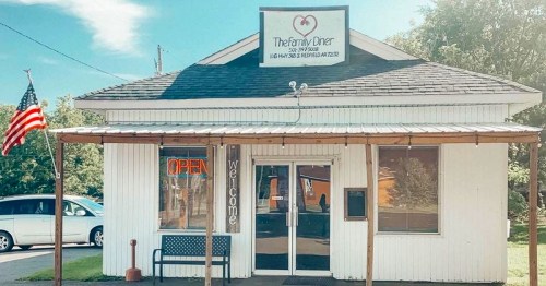 A small diner with a sign reading "The Family Diner," featuring an open sign and a bench outside. An American flag is visible.