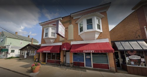 A two-story bakery with red awnings and a sign reading "Frank's Pastry," located on a street with nearby shops.