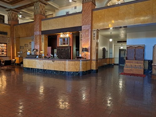 A spacious hotel lobby featuring a reception desk, elegant decor, and polished tile flooring.