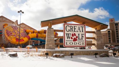 Sign for Great Wolf Lodge with colorful water slides in the background and snow on the ground.