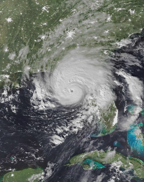 Satellite image of a large hurricane approaching the Gulf Coast, with swirling clouds and surrounding ocean.
