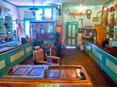 A vintage barbershop interior with wooden floors, old barber chair, shelves, and various antique items.