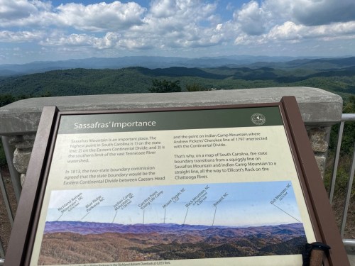Sign about Sassafras Mountain's importance, overlooking a scenic view of mountains and valleys in South Carolina.