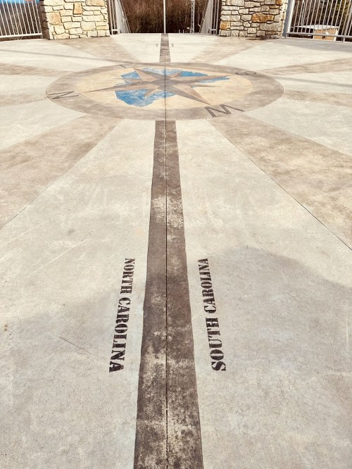 A compass rose design on a concrete surface, featuring the names "North Carolina" and "South Carolina."