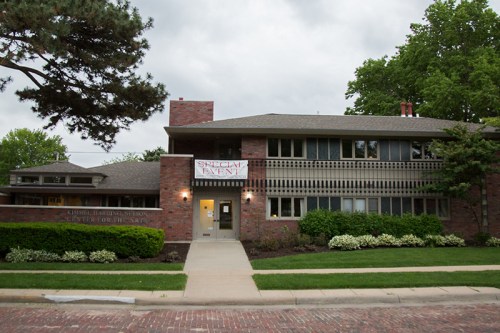 A brick building with large windows and a banner reading "Special Event" in front, surrounded by greenery.