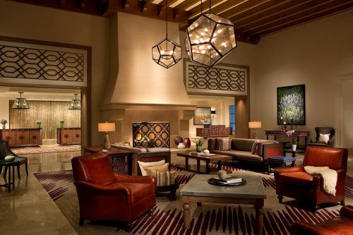 Cozy lobby with modern decor, featuring leather chairs, a fireplace, and stylish lighting fixtures.