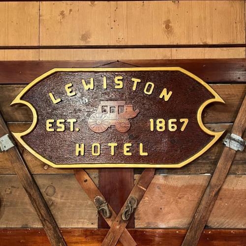 Wooden sign for Lewiston Hotel, established in 1867, featuring a vintage carriage design.
