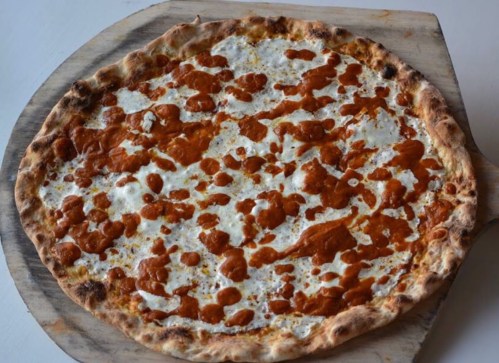 A freshly baked pizza with a golden-brown crust and a creamy, orange sauce topping.