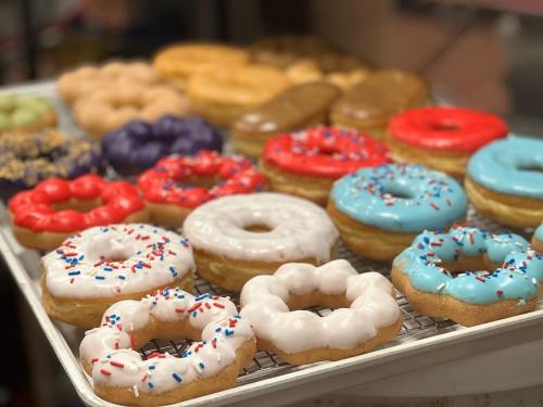 A variety of colorful donuts on a tray, featuring sprinkles and different icing flavors.