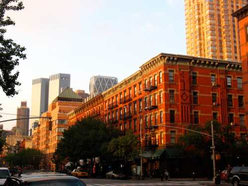 Sunset view of a city street featuring historic brick buildings and modern skyscrapers in the background.