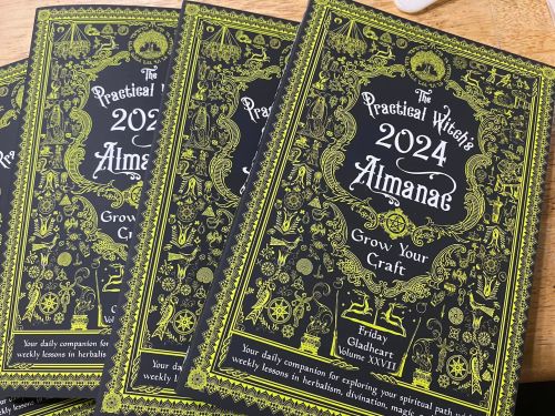 Four copies of "The Practical Witch's 2024 Almanac" featuring intricate black and gold designs on the covers.