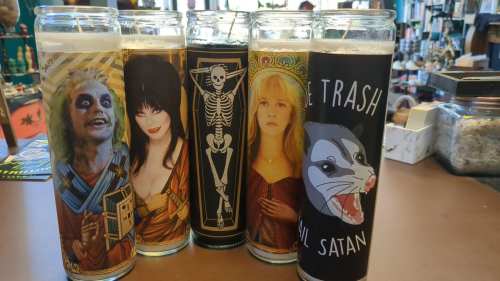 Five decorative candles featuring spooky characters and designs, including a skeleton and a cartoonish badger.