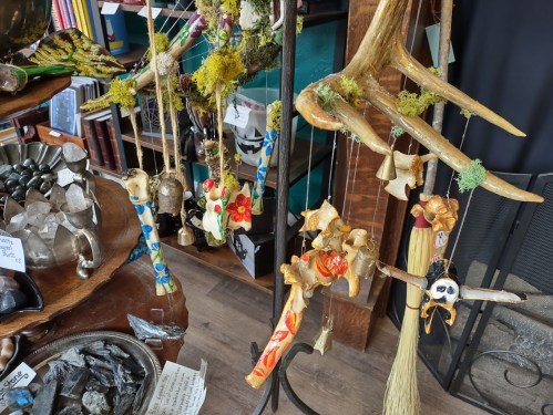 Colorful handmade ornaments and decorations hanging from a display, surrounded by various natural materials and crafts.