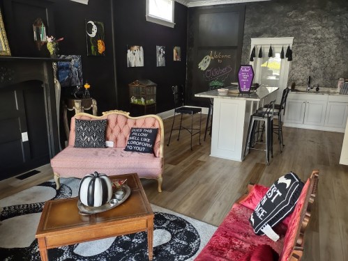 A stylish interior featuring a black wall, cozy seating, a kitchen island, and decorative elements for a welcoming atmosphere.