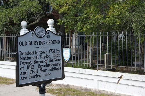 Sign marking the Old Burying Ground, noting its history and the soldiers buried there. Trees and a fence are visible in the background.