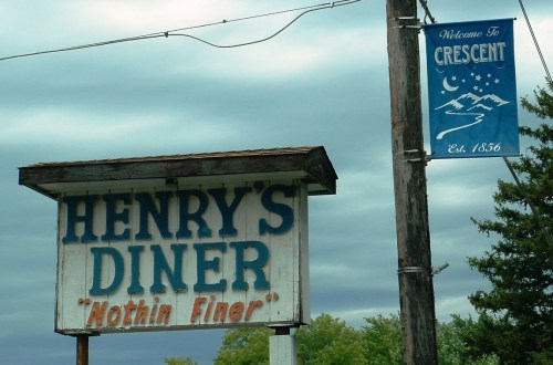 Sign for Henry's Diner with the slogan "Nothin' Finer" and a welcome banner for Crescent, established 1856.