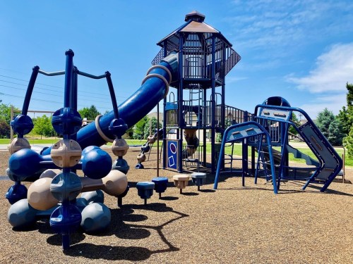 A colorful playground featuring a large slide, climbing structures, and various play equipment on a sunny day.