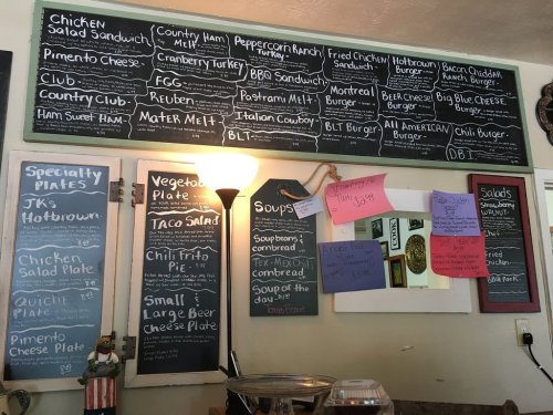 Menu board featuring various sandwiches, salads, soups, and daily specials in a casual dining setting.