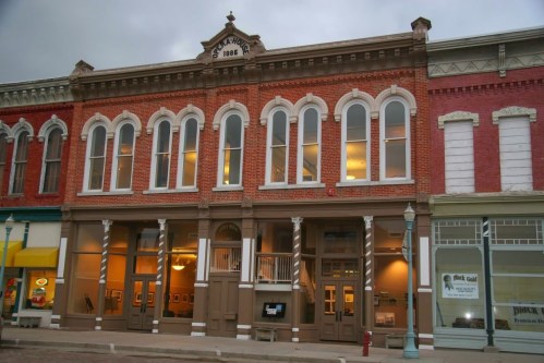 Historic brick building with large windows, featuring a steakhouse sign and a mix of architectural styles.