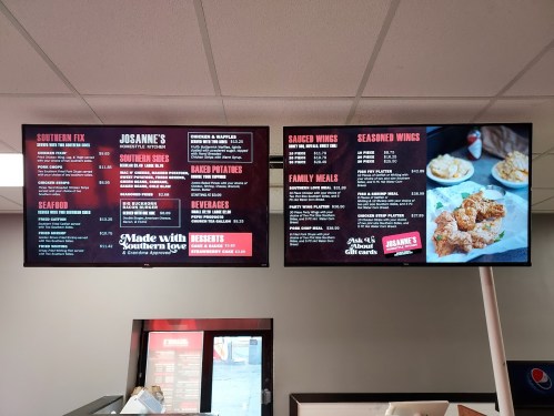 Menu boards displaying food options like Southern dishes, seafood, wings, beverages, and family meals at a restaurant.