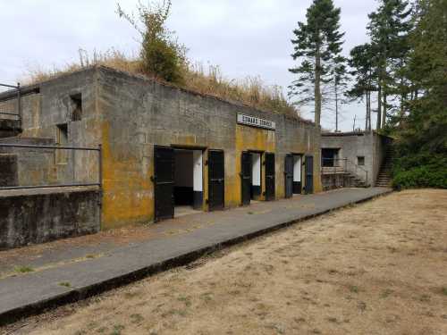 Abandoned concrete building with a sign reading "Battery Turner," surrounded by dry grass and trees.