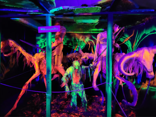 A spooky display featuring glowing skeletons of horses and a zombie figure in a dark, eerie setting.
